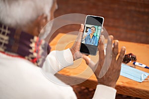 Shoulder shot of Old man on video with to doctor on mobile phone - concept of nurse Online Chat, telehealth, or tele photo