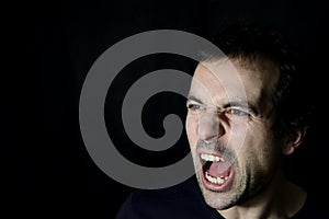 Shouting angry young man, black background