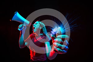Shouting with megaphone. Young woman with smoke and neon light on black background. Highly tensioned, wide angle, fish