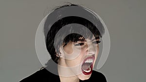 Shouting mouth, screaming face. Portrait of beautiful emotional woman with angry grimace on face, to be aggressive.