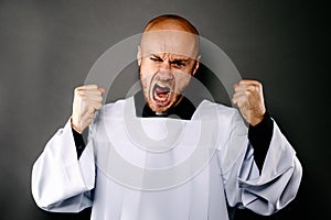 Shouting upset catholic priest in white surplice photo