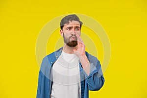 Shouting young man with his mouth wide open. Male model in a blue shirt on a yellow background. Emotions, advertisement