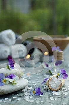 Shovel with bath salt and massage oil on the background of a set for spa treatments and burning candles in the summer