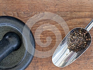 Shovel with black pepper and a mortar with pestle
