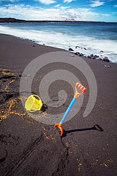 shovel and children\'s play bucket on a black sand beach photo