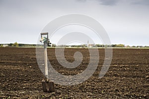 Shovel with glowes on cultivated farm field