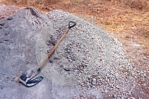 The shovel is lying on a pile of sand and gravel.