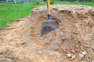 Shovel in a pile of construction gravel on a garden plot, side view, close-up