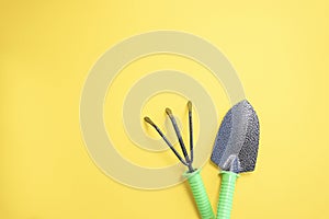 shovel and rake on a yellow background. backyard vegetable garden planting concept with copy space. Soft focus.