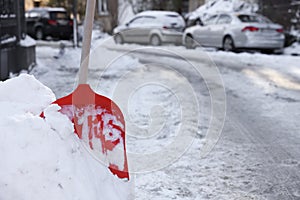 Shovel in snowdrift on city street. Space for text