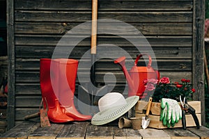 Shovel, watering can, hat, rubber boots, box of flowers, gloves and garden tools