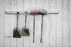 Shovels and rakes hanging outside a stable photo