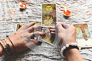 Show fortune tellers of hands holding tarot cards and tarot reader with candle light on the table, Performing readings magical