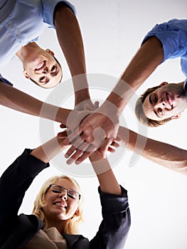 A show of team spirit in the office. Low angle shot of a business team putting their hands in a huddle.