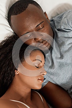 They show their love even when being asleep. a tired young couple sleeping comfortably together in their bed at home in