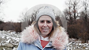 Show toungue piercing young woman looking at camera in hat with northern wind 4K