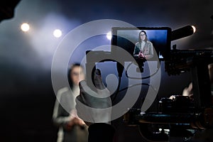 Portrait of women speaking through a microphone in dark conference hall. woman talks into microphones at press