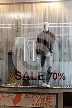 Showcase of clothing store in season of discounts, mannequin in modern comfortable men`s clothing, inscriptions of discount 70, 8