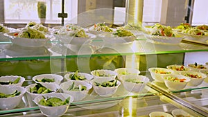 Showcase with different freshly prepared vegetable salads in self-service cafeteria or buffet restaurant. health food