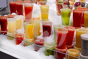 Showcase with different types of colorful cold juice and smoothie in the ice.