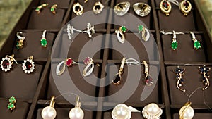 Showcase with jewelry earrings with precious stones, Jewellery on store display, Gold jewelry for woman, exposed for