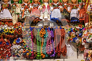 Showcase with many dolls in national costumes, multi-colored wooden beads and wreaths of bright flowers.