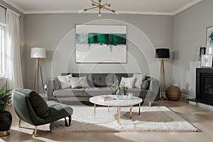 Abstract painting on grey wall o contemporary living room interior with emerald green armchair with round pillow, commode and couc