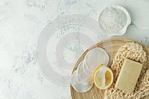 Shower accessories - massage brush, sponge, lemon, sea salt, soap on a light background, top view. Cleansing of the skin, scrub,