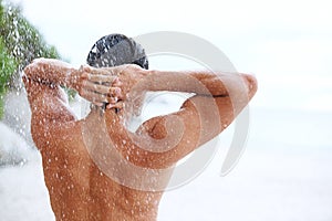 Shower, beach and man with water for cleaning, washing hair and grooming for healthy skin. Beauty, nature and back of