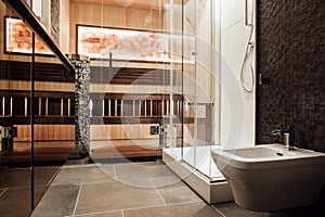 The shower with a bidet, a glass shower and a sauna behind a glass door