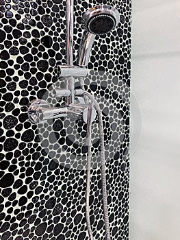 Shower cabin with chrome head and faucet decorated with black pebbles