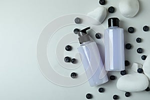 Shower gels, blueberry and stones on white background