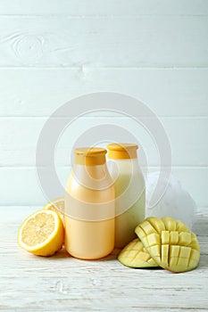 Shower gels, mango and lemon on white wooden background