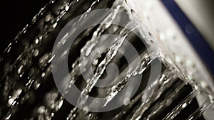 Shower head macro slow motion with running water on dark background