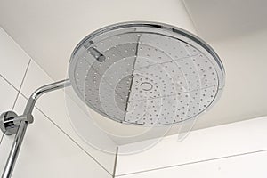 Shower head in modern white tiled bathroom