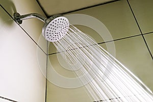 Shower head with refreshing water droplets spraying down in bath