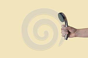Shower head in woman hand on a beige background photo