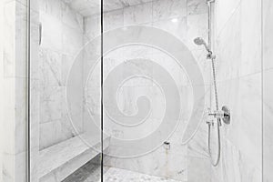 A shower with marble tiles and chrome showerhead.