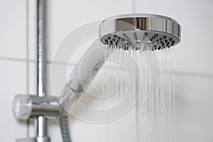 Shower with modern showerhead and running water in bathroom