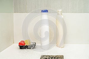 shower stall with a stainless steel drain with bottles of shampoo and soap bars splashed by the shower water