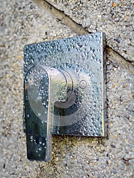 Shower tap faucet in chrome on stone wall. Water drops on metal