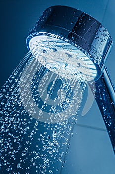 Shower Head with Water Stream on Blue Background photo