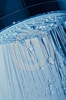 Shower Head with Water Stream on Blue Background photo
