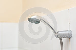 Showerhead in the bath. Hanging shower head in the old style bathroom with tile walls