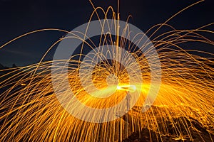 Showers of hot glowing sparks from spinning steel wool on the rock