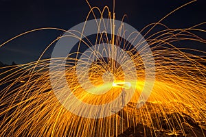 Showers of hot glowing sparks from spinning steel wool on the rock photo