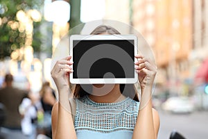 Showing a blank tablet screen covering her face