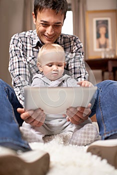 Showing dad how its done. A young father showing his baby girl how his digital tablet works.