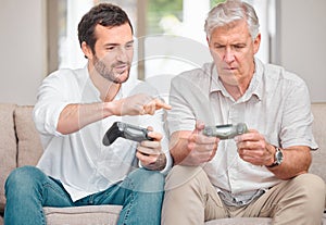 Showing dad what this whole gaming things is all about. a handsome young man showing his senior father how to play video