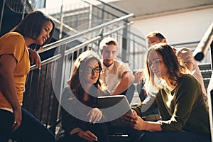 Showing her results to the team. Low angle shot of two young designers looking at a digital tablet while gathered in a